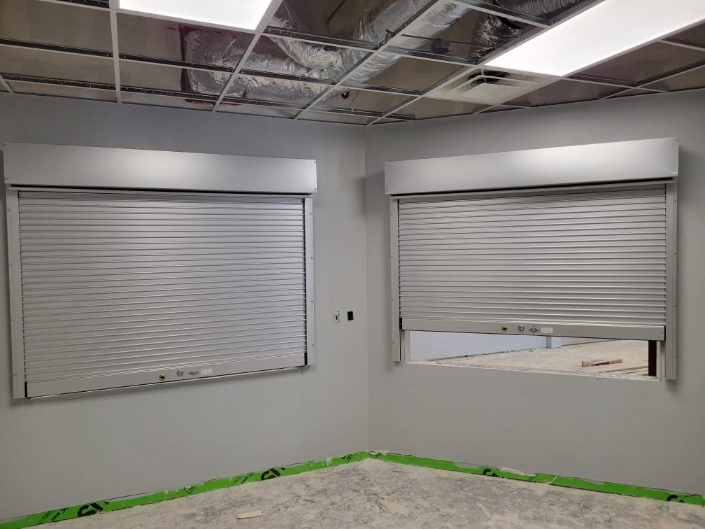 A room featuring two roller shutters and a window, showcasing a blend of functionality and natural light.
