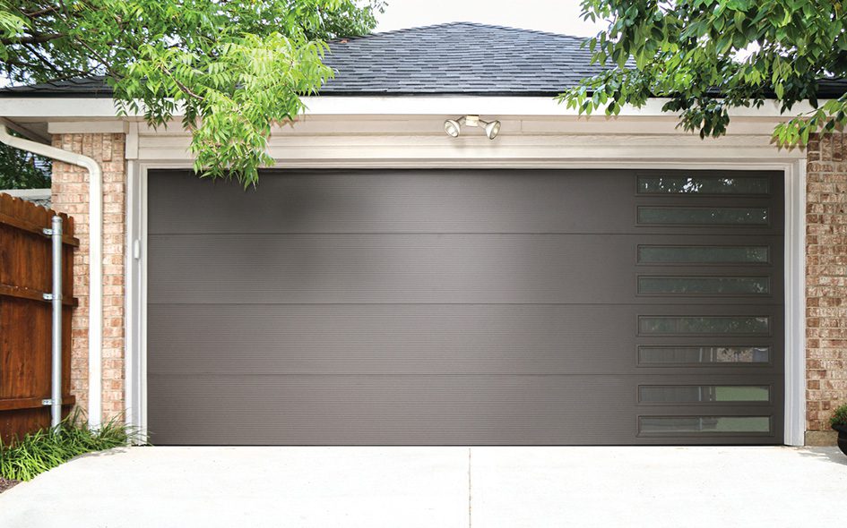 A gray garage door is framed by a vibrant tree, enhancing the peaceful ambiance of the setting.